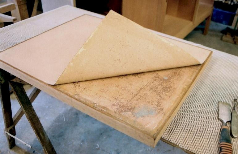 Bijzettafel met marmoleumbladafwerking. Een oude reparatie. Ergens in de afgelopen jaren heeft men de originele marmoleum top vervangen door kunstleer.