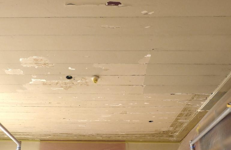 Beschilderd plafond schoonmaken van overschildering.